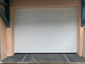 Porte de garage enroulable motorisée blanche avec caillebotis pour passage de véhicule