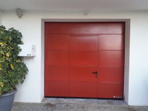Porte de garage sectionnelle motorisée rouge basque avec portillon Hörmann installé par AED64